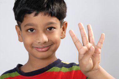 Güney Asyalı çocuk beyaz stüdyo arka planında 4 parmak gösteriyor.