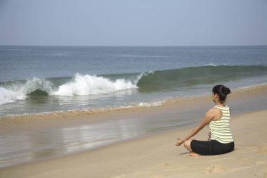 Güney Asyalı genç bayan yoga yapıyor. Padsu duruşu yapıyor. Shiroda, Dist Sindhudurga, Maharashtra, Hindistan 'da. 