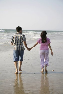 Güney Asyalı genç adam ve kadın el ele tutuşuyorlar. Birlikte yürüyorlar. Shiroda, Dist Sindhudurga, Maharashtra, Hindistan 