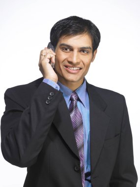 Güney Asyalı yönetici beyaz arka planda cep telefonuyla konuşuyor.