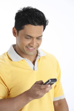 Kendine güvenen genç adam cep telefonuna bakıyor. Sağ elini tutuyor ve numarayı çeviriyor. 