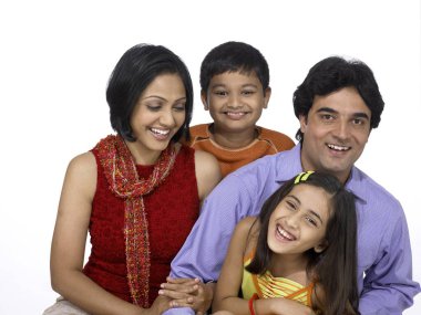 Güney Asyalı aile baba, anne ve kız gülümseyen ve kameraya bakan.