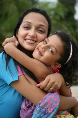 Güney Asyalı anne ve kız birbirlerine sarılıyorlar ve gülümsüyorlar MR3687H687E