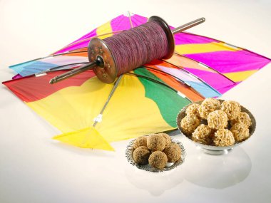Renkli beş uçurtma Makara Sankranti festivalinde susamlı pirinç laddoo ile iple manja ipliği