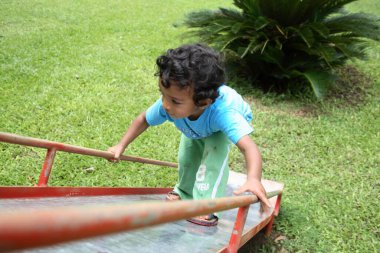 Güney Asyalı küçük çocuk kaydırağın üstünde oynuyor.