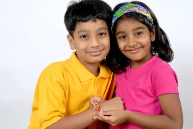 Güney Asyalı Hintli kız kardeş rakhi ile raksha Bandhan festivalini beyaz stüdyo arka planında yapıyor.