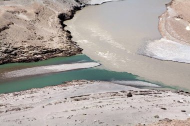 Confluence of green water of Indus river and muddy brown water of Zanskar River near Nimmu on Ladakh, Jammu and Kashmir, India  clipart