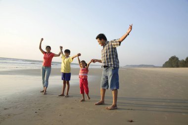 Güney Asyalı ebeveynler ve çocuklar deniz kıyısında el ele tutuşuyorlar, Shiroda, Dist Sindhudurga, Maharashtra, Hindistan 