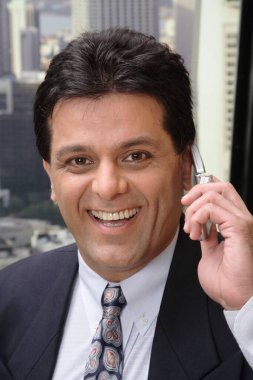 Ofiste cep telefonundan konuşan yönetici modern şehrin en üst katındaki gökdelende konuşuyor. 