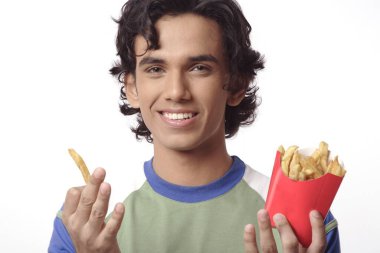 Bir paket patates cipsi ya da patates kızartması tutan genç bir çocuk. 