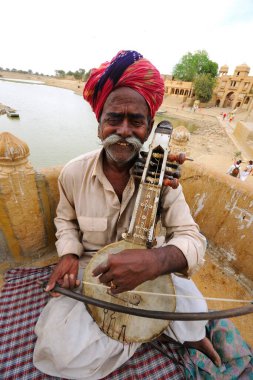 Gadsisar Gadisar Gölü, Jaisalmer, Rajasthan, Hindistan 'da müzik aleti çalan halk müzisyeni. 