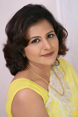 Güney Asyalı genç bayan pembe sari giyiyor ve gülümsüyor. 