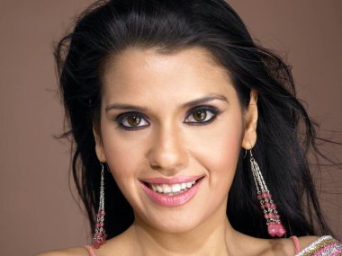 Güney Asyalı kadın gülümsüyor ve kameraya bakıyor. 