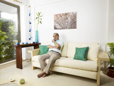 Kanepede oturan yaşlı adam.