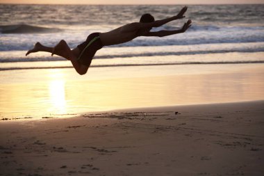 Deniz kıyısındaki dalgaların içine dalan genç çocuk