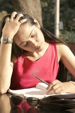 Yol kenarındaki restoranda kitap okuyan Hintli genç kız.