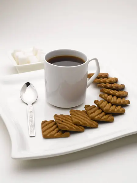 stock image mug of black tea in serving plate with sugar cubes and biscuits India