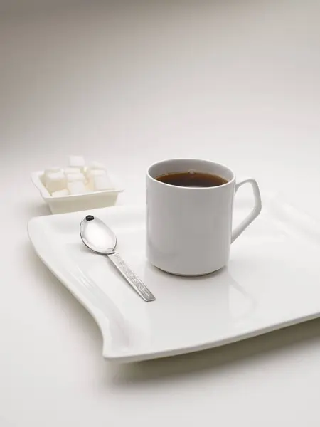 stock image mug of black tea in serving plate with sugar cubes India