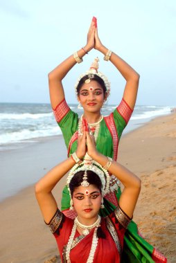 Dancers performing classical traditional odissi dance in front of bay of Bengal sea, Konarak, Orissa, India   clipart
