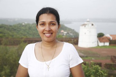 Arka planda Aguada Kalesi 'nin feneri gülümseyen bayan.