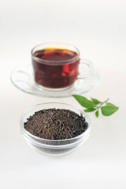 Çaydanlıkta çay tozu ve beyaz arka planda çay fincanı.