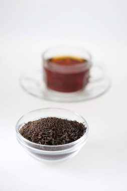 Çaydanlıkta çay tozu ve beyaz arka planda çay fincanı.