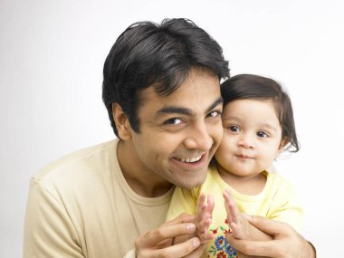 Hintli baba küçük kızın yüzüne üflüyor. 