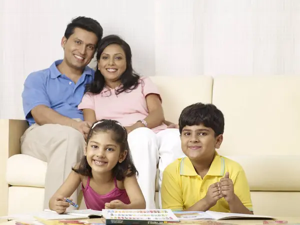 stock image Children doing drawing work parents sitting behind them in house 