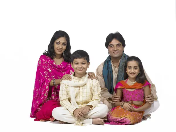 Stock image South Asian Indian family with father mother son and daughter sitting smiling and looking at camera 