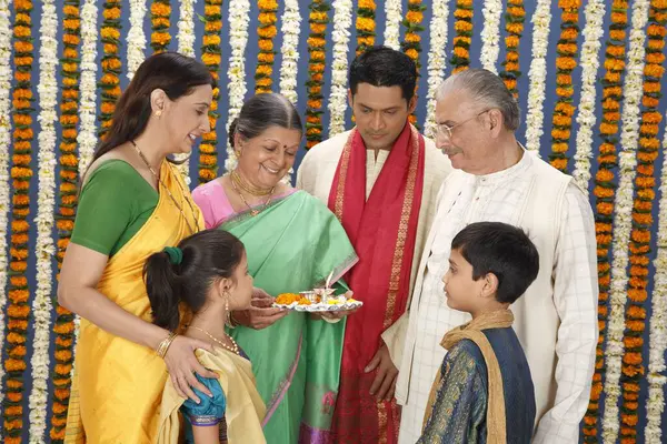 Stock image Grandmother holding aarti thali and family looking 