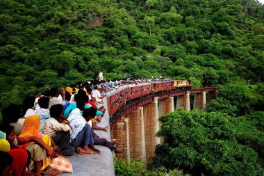 Köprüdeki trenin çatısında oturanlar Kemali Ghat, Rajasthan, Hindistan