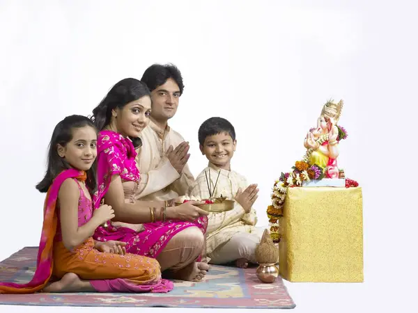 stock image South Asian Indian family with father mother son and daughter sitting praying to lord Ganesha  