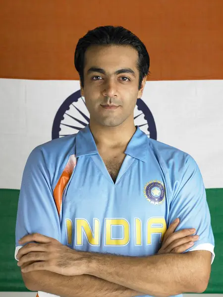 stock image Indian cricket player standing with hands folded in front of flag of India in background 