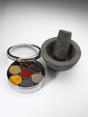 Different types of spices in bowls in stainless steel box with old stone grinder clipart