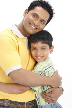 Baba ve oğul birbirlerine sevgiyle sarılıyorlar. Beyazların arka planında izole edilmiş.