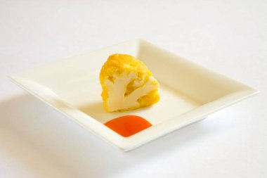 Hint mutfağı, fast food aperatifleri Phoolgobi Ke Pakode çıtır çıtır karnabahar pufları beyaz arka planda domates ketçapıyla servis ediliyor.