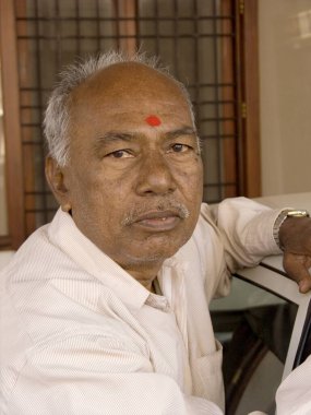 Alnında kırmızı tilak olan yaşlı Hintli adam kameraya bakıyor. 