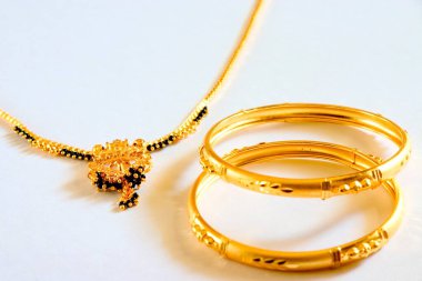 gold and black beads necklace mangalsutra Hindu bride symbol of marriage with gold bangles imitation jewellery on white background
