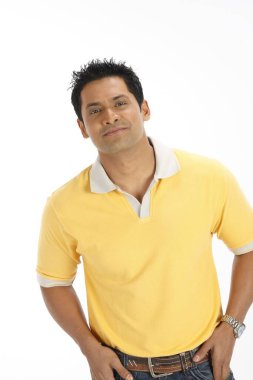 Kendine güveni tam genç bir adam kot pantolonun cebinde, sarı tişört giyiyor. 