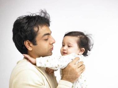 Hintli baba küçük kızın yüzüne üflüyor. 