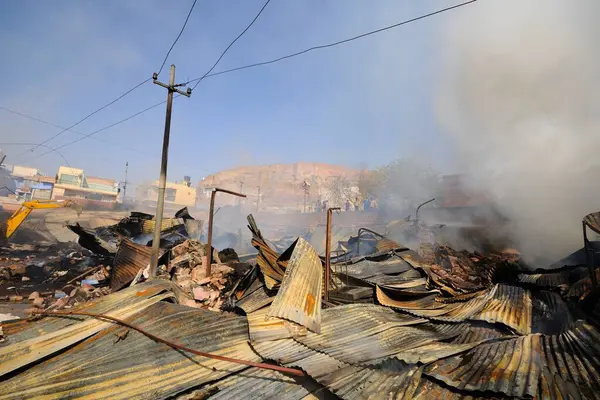 stock image Jcb operator demolish shops while summer market anaaj mandi on fire, Jodhpur, Rajasthan, India 