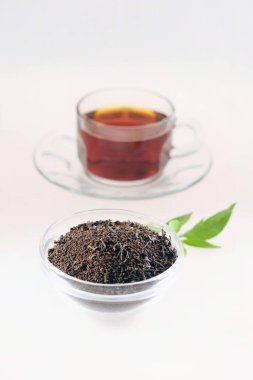 Çaydanlıkta çay tozu ve beyaz arka planda çay fincanı.