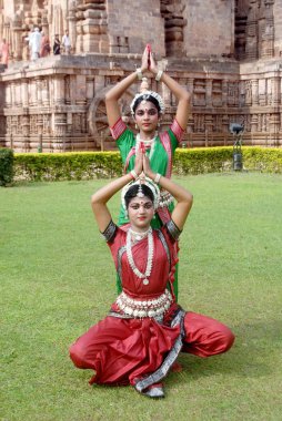Dancers performing classical traditional odissi dance on lawn   clipart