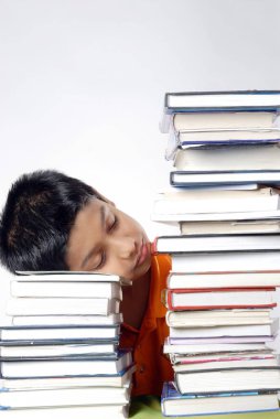 Çocuk kafasını kitapların üzerine koymuştu. 