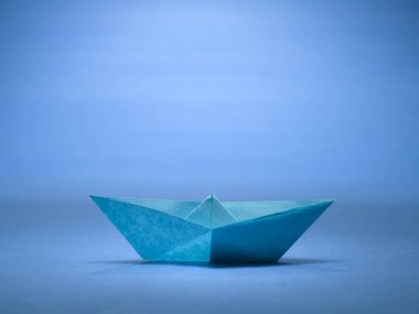 Mavi arka planda origami teknesi, stüdyo çekimi.