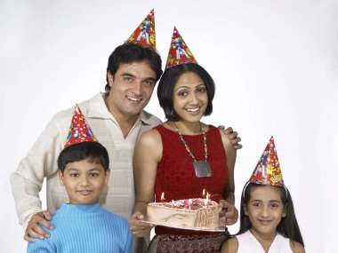 Güney Asyalı bir aile baba, anne ve kız ellerinde doğum günü pastası taşıyorlar. 