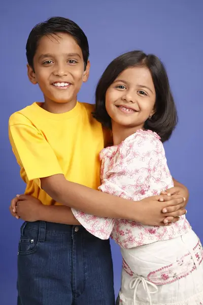 stock image Ten and eight year old boy and girl standing and holding each other 