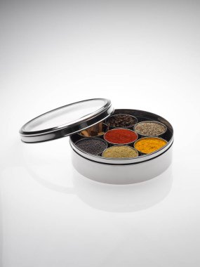 Different types of spices in bowls in stainless steel box on white background clipart