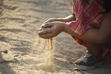 Genç Hintli kız elinde kumla oynuyor. 