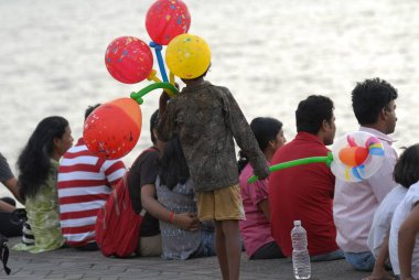 Young boy sells colourful balloons to tourists visiting Marine Drive in Bombay Mumbai, Maharashtra, India  clipart